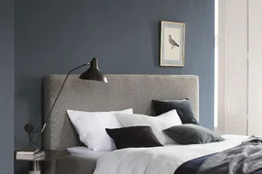 Gemachtes Bett mit grauem Kopfteil